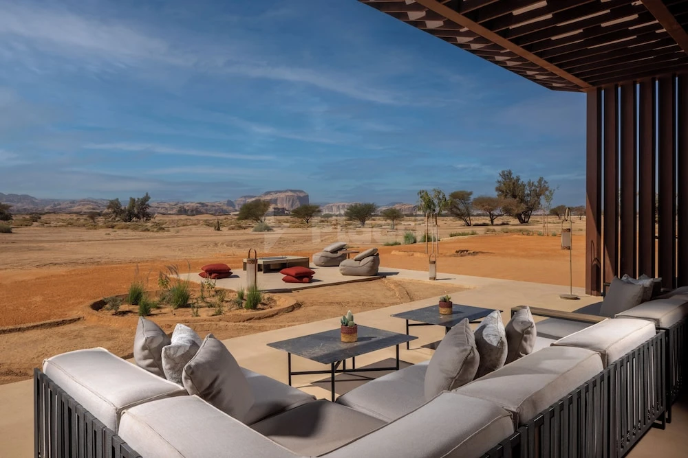 Outdoor lounge at The Chedi Hegra, AlUla, with desert vista and low-slung seating under wooden canopy