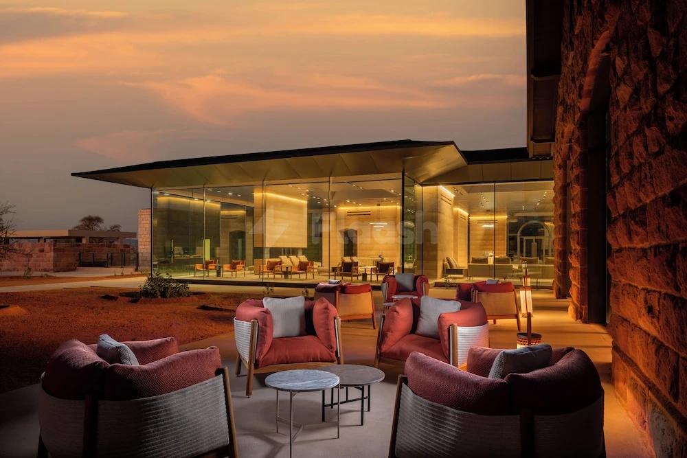 Outdoor lounge at The Chedi Hegra, AlUla, with plush armchairs and warm ambient lighting against stone walls