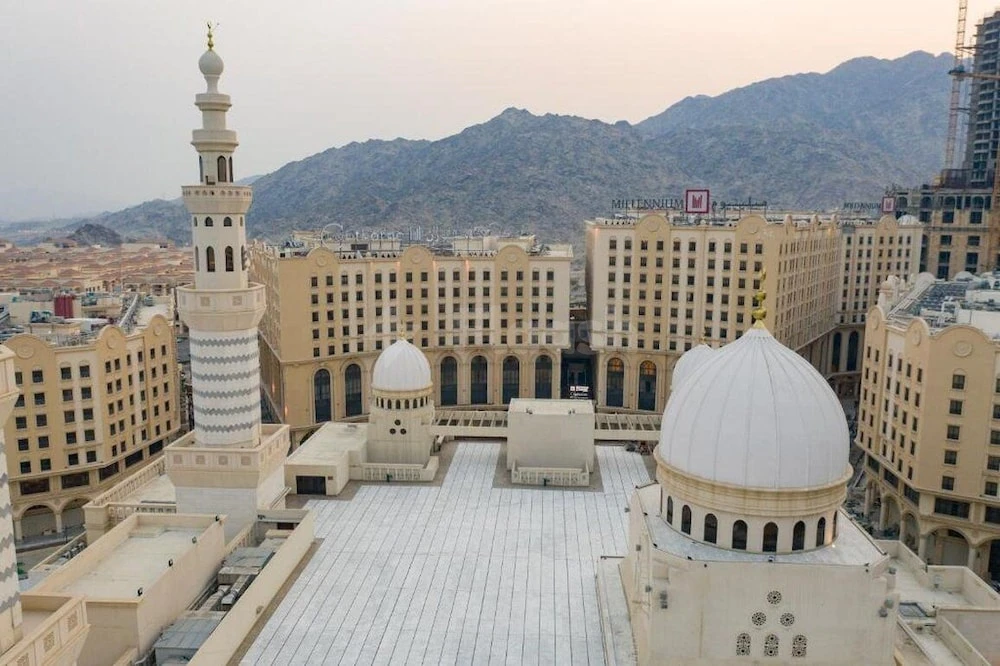 Rooftop terrace at Copthorne Makkah Al Naseem, Mecca, with white domes and minaret against mountain backdrop