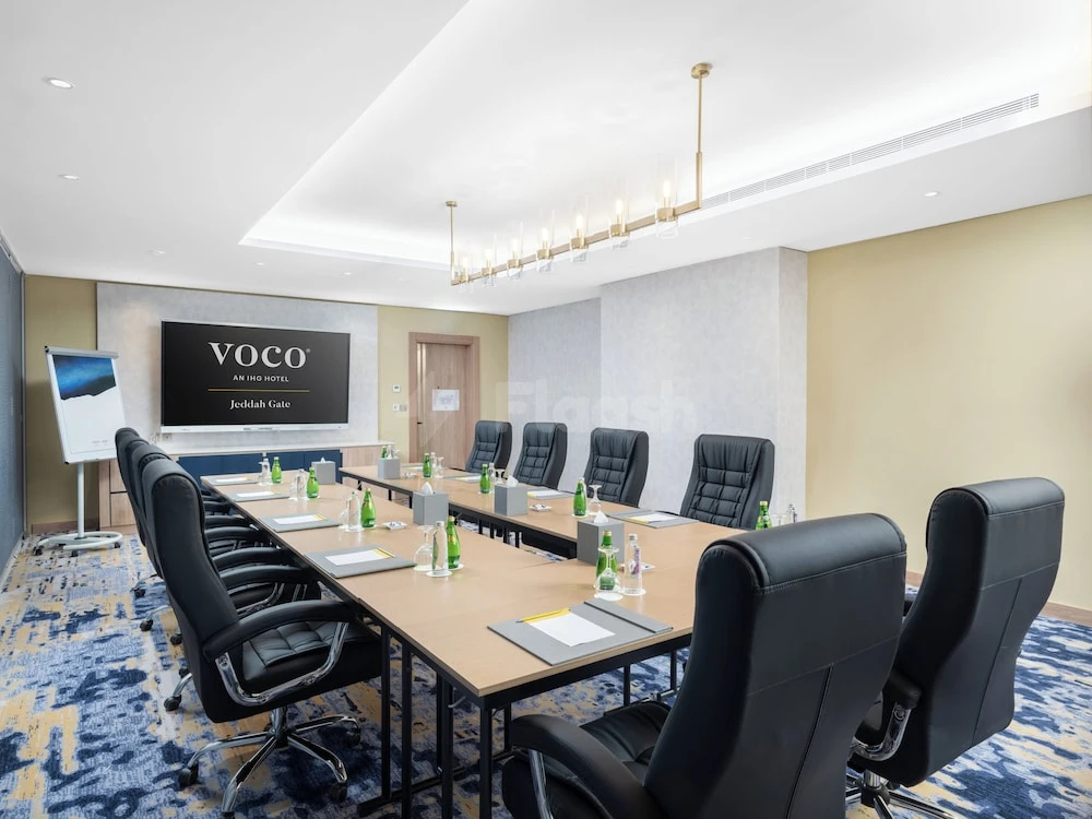 Conference room at voco Jeddah Gate, Djeddah, with branded screen and modern pendant lighting