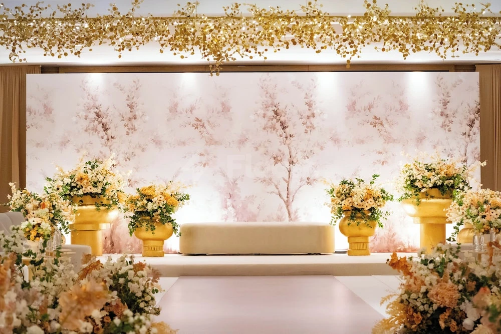 Wedding stage at voco Jeddah Gate, Djeddah, adorned with golden floral arrangements and soft pink backdrop