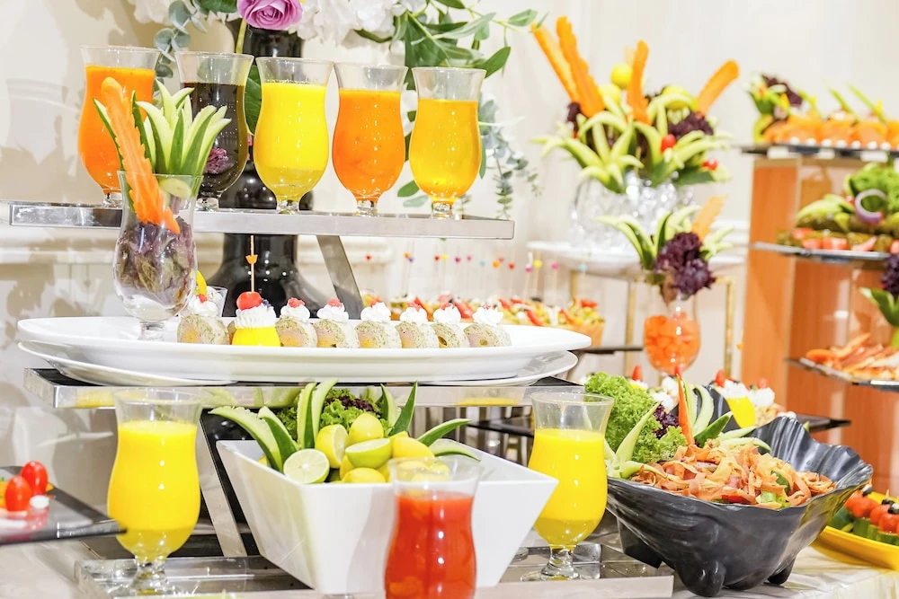 Buffet spread at Emaar Al Manar Hotel, Makkah, featuring tiered platters of colorful juices, garnished dishes, and floral