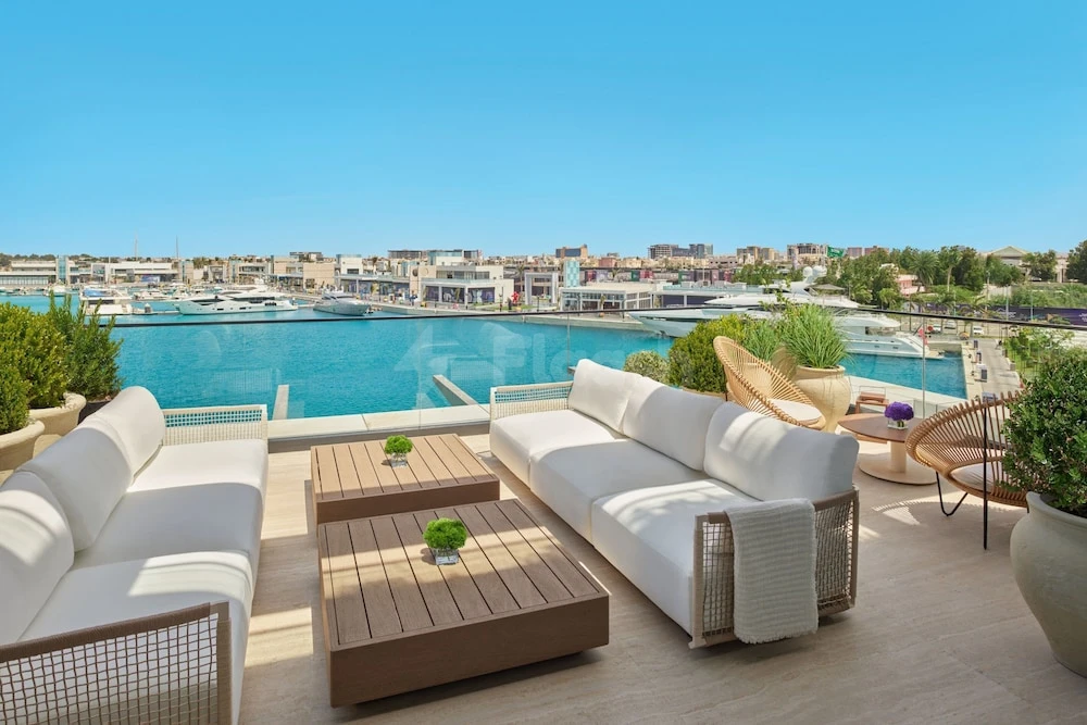 Rooftop terrace at The Jeddah EDITION, Jeddah, with white sofas and wooden tables facing the marina