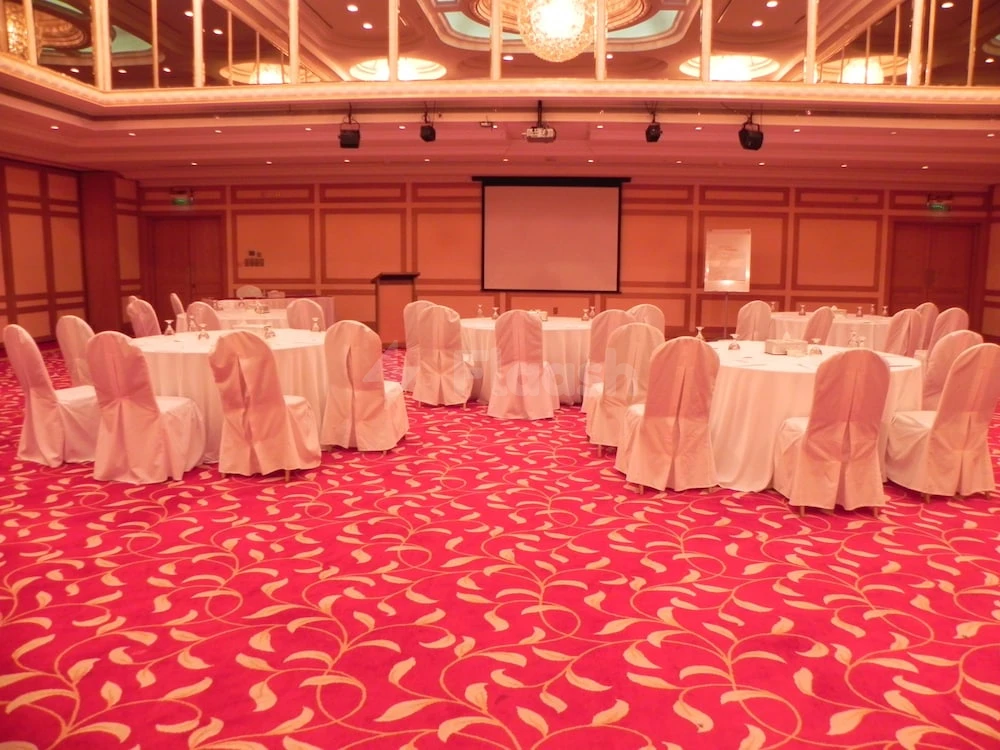 Banquet hall at Millennium Downtown Abu Dhabi, Abu Dhabi, with red patterned carpet and white draped tables