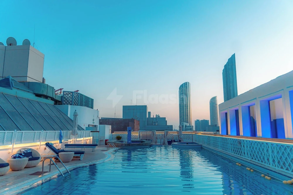 Rooftop infinity pool at Millennium Downtown Abu Dhabi, Abu Dhabi, with blue-lit arches and lounge chairs under twilight