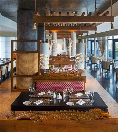 Dining area at Le Méridien Al Aqah Beach Resort, Fujairah, with wooden beams and patterned table settings