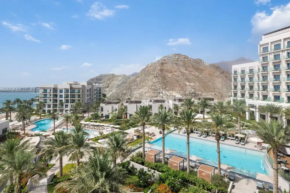 Pool terrace at Address Beach Resort Fujairah, Fujairah, with palm trees and mountain backdrop