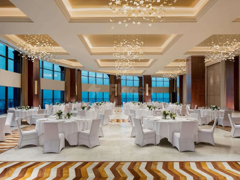 Banquet hall at Fairmont Ajman, Ajman, with white linens and crystal chandeliers above patterned flooring