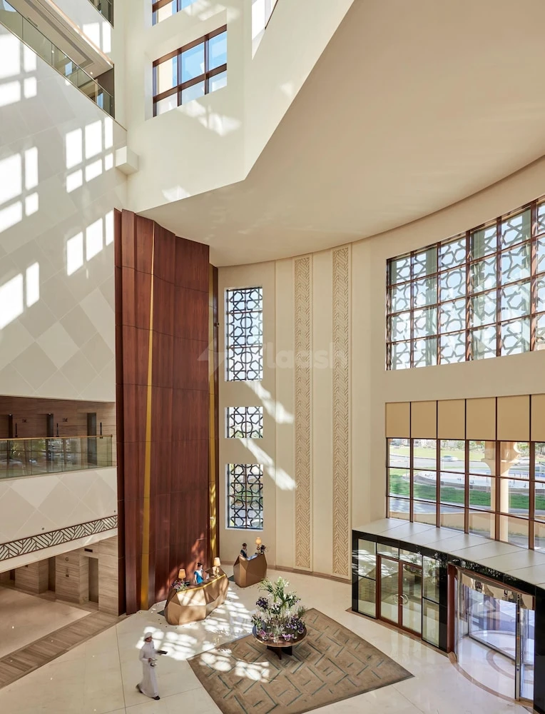 Grand lobby at Fairmont Ajman, Ajman, featuring tall wooden panels and geometric lattice windows casting light patterns