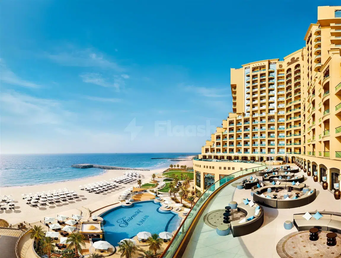 Outdoor terrace at Fairmont Ajman, Ajman, overlooking beach and pool with lounge seating and blue accents