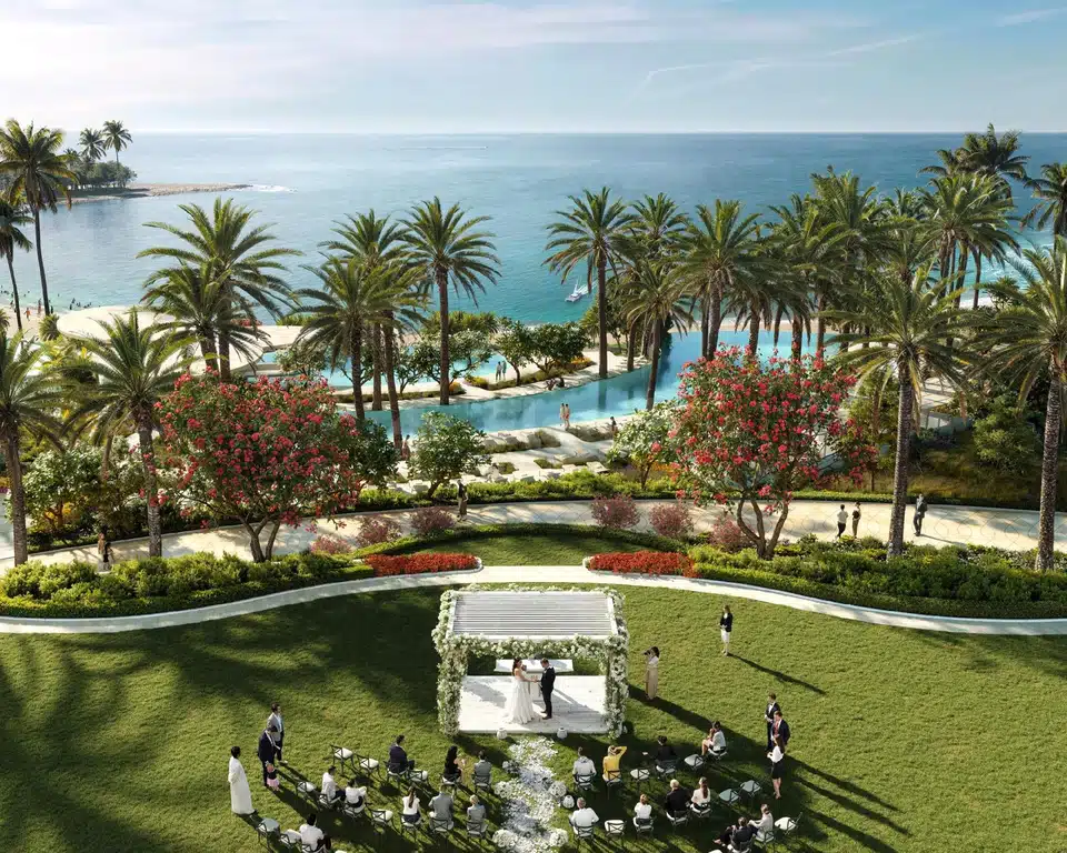 Outdoor ceremony lawn at Wynn Al Marjan Island, Ras Al Khaimah, with floral arbor and palm trees overlooking