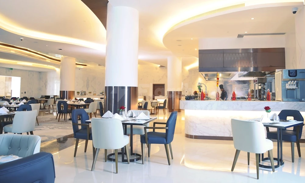 Dining area at Royal M Al Aqah Beach Resort, Fujairah, with blue and beige chairs and marble-topped tables