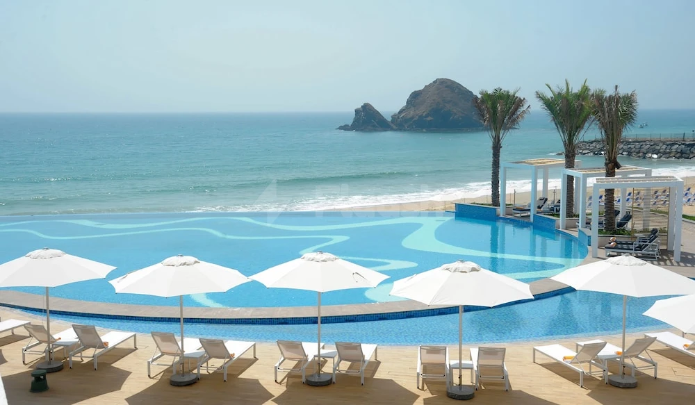 Infinity pool at Royal M Al Aqah Beach Resort, Fujairah, facing turquoise sea with rocky islets and white4