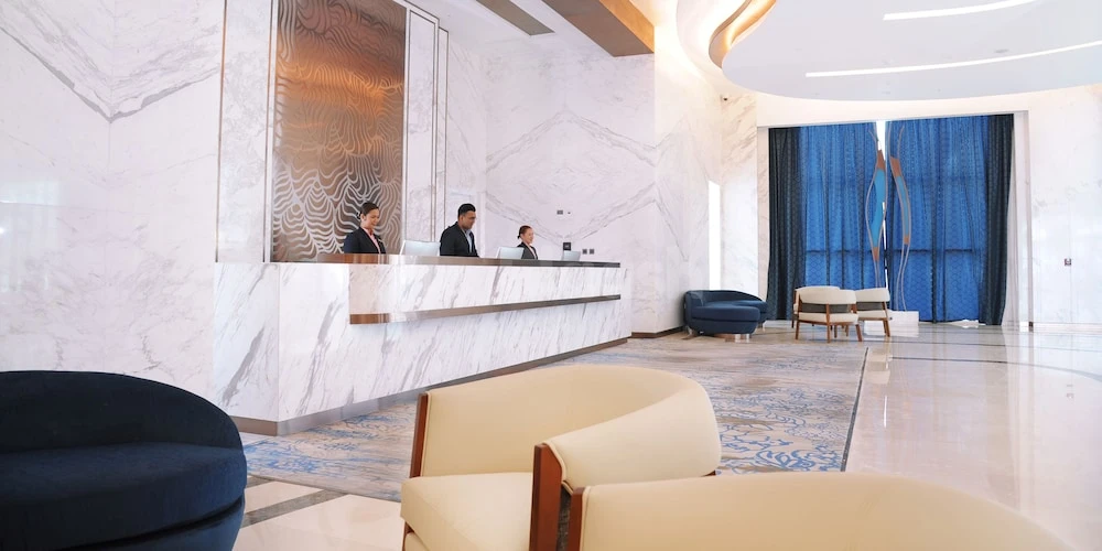 Marble lobby at Royal M Al Aqah Beach Resort, Fujairah, with reception desk and blue drapes