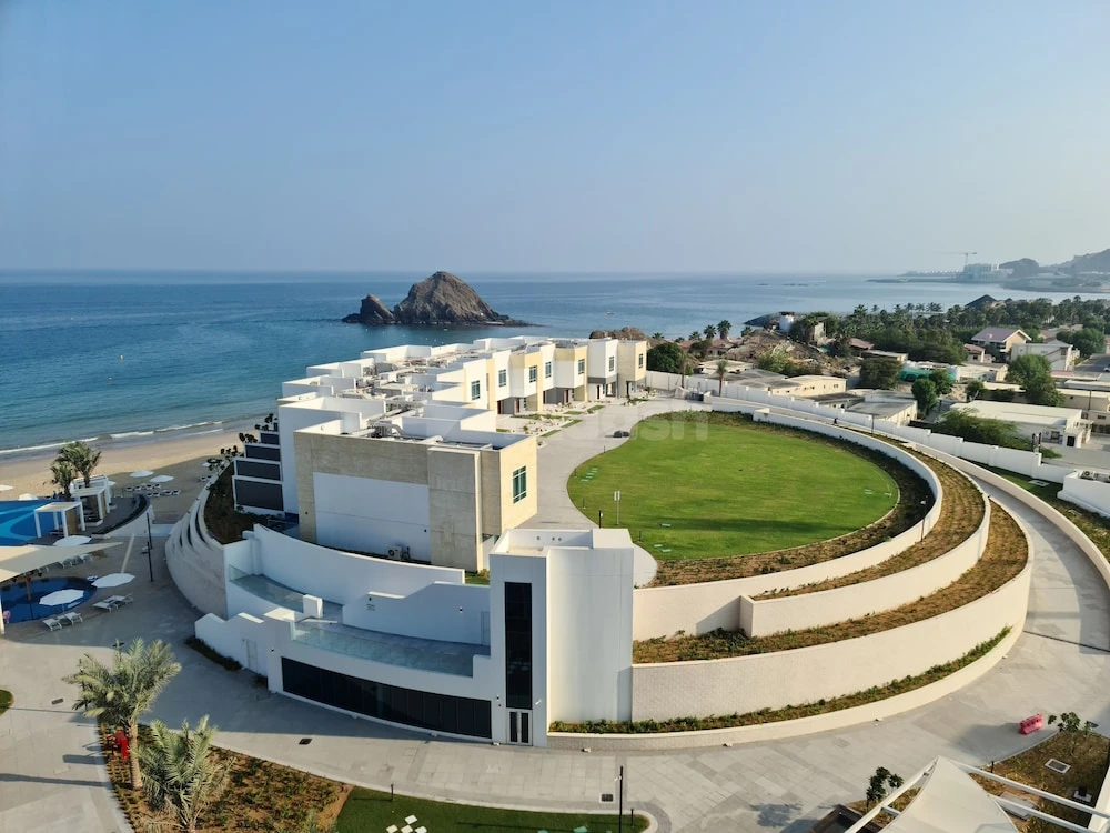 Terraced lawn at Royal M Al Aqah Beach Resort, Fujaira, with circular green space and seaside backdrop