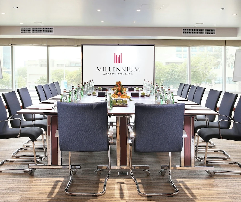 Boardroom at Millennium Airport Hotel Dubai, Dubai, with branded screen and floral centerpiece