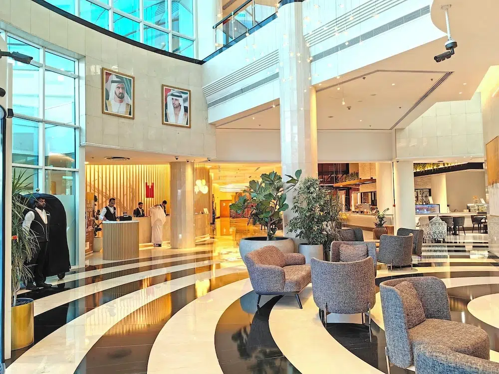 Lobby at Millennium Airport Hotel Dubai, Dubai, with curved marble flooring and framed portraits on walls