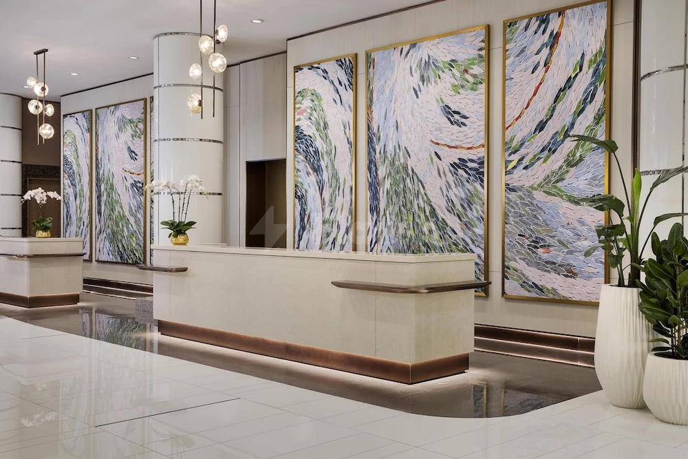 Lobby at Hilton Dubai Jumeirah, Dubai, featuring abstract wave paintings and modern pendant lights over marble floors