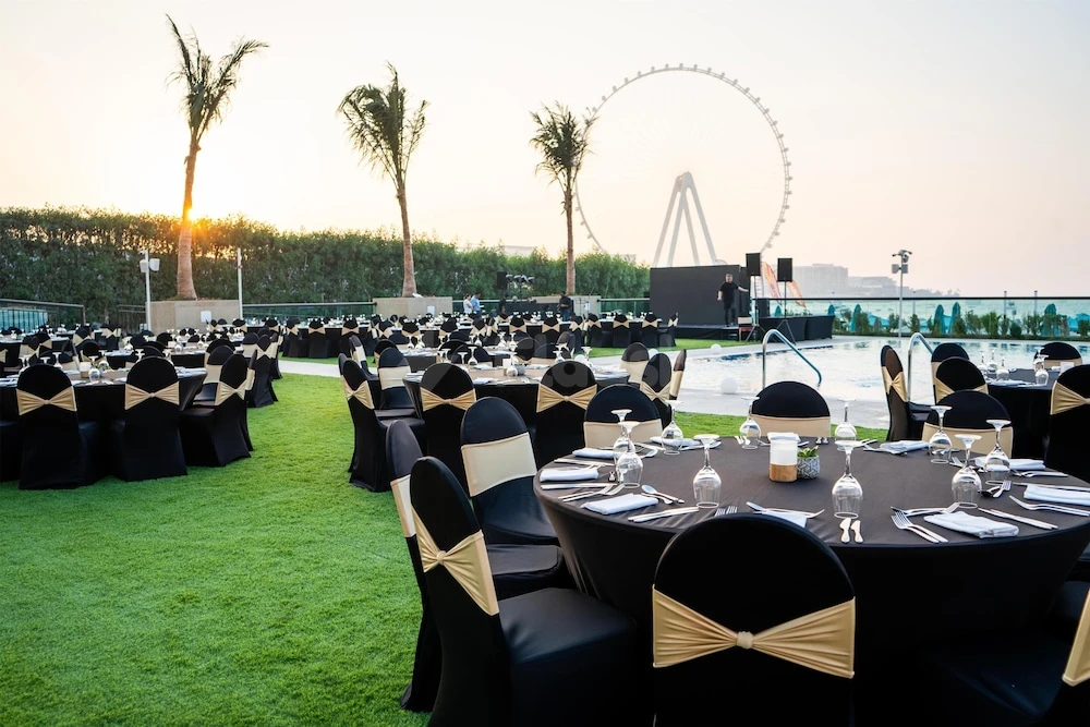 Outdoor event space at Hilton Dubai Jumeirah, Dubai, with artificial turf and Dubai Eye visible beyond the pool