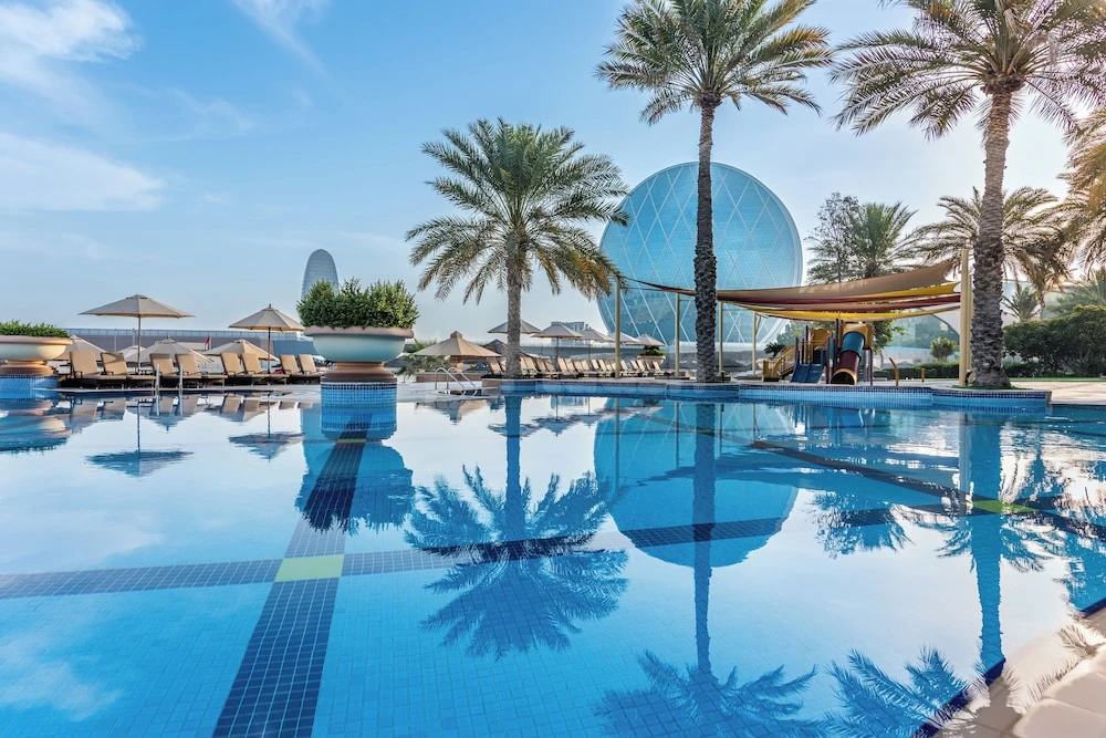 Infinity pool at Al Raha Beach Resort & Spa, Abu Dhabi, reflecting palm trees and a glass dome under