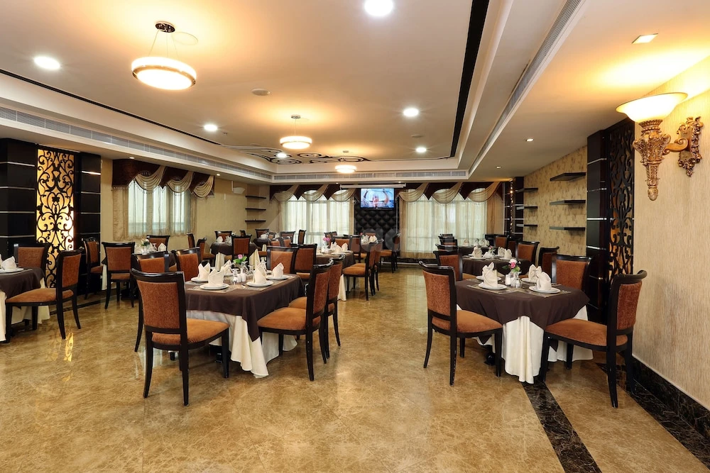 Dining room at Royal Grand Suite Hotel, Sharjah, with patterned wall panels and recessed ceiling lights