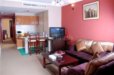 Living room at Al Bustan Tower Hotel Suites, Sharjah, with purple pink walls and wooden TV stand