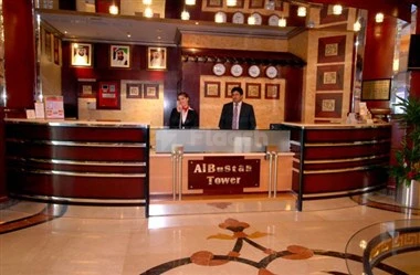 Reception area at Al Bustan Tower Hotel Suites, Sharjah, featuring polished marble floors and a modern wooden front