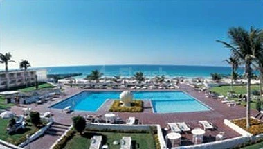 Poolside lounge at Lou Lou'a Beach Resort, Sharjah, with turquoise pool and ocean view under clear blue sky