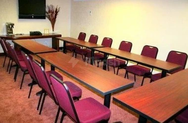 Conference room at Al Hayat Hotel Apartments, Sharjah, with wooden tables and maroon chairs arranged in rows under