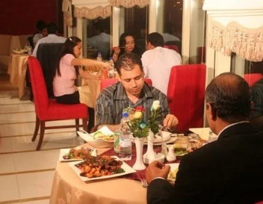 Dining area at Al Hayat Hotel Apartments, Sharjah, with red upholstered chairs and floral table centerpieces