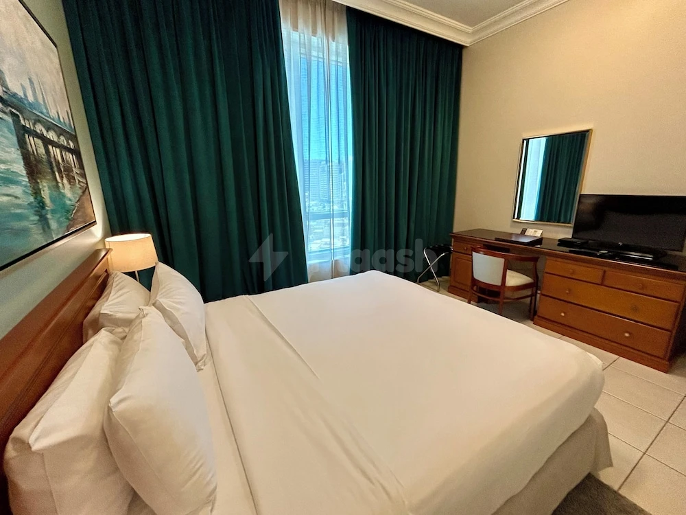 Guest room at Al Nakheel Hotel Apartments, Abu Dhabi, featuring emerald drapes and city view through large window