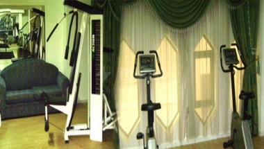 Fitness gym at Royal Crown Hotel, Sharjah, with treadmills and weight benches near curtained windows