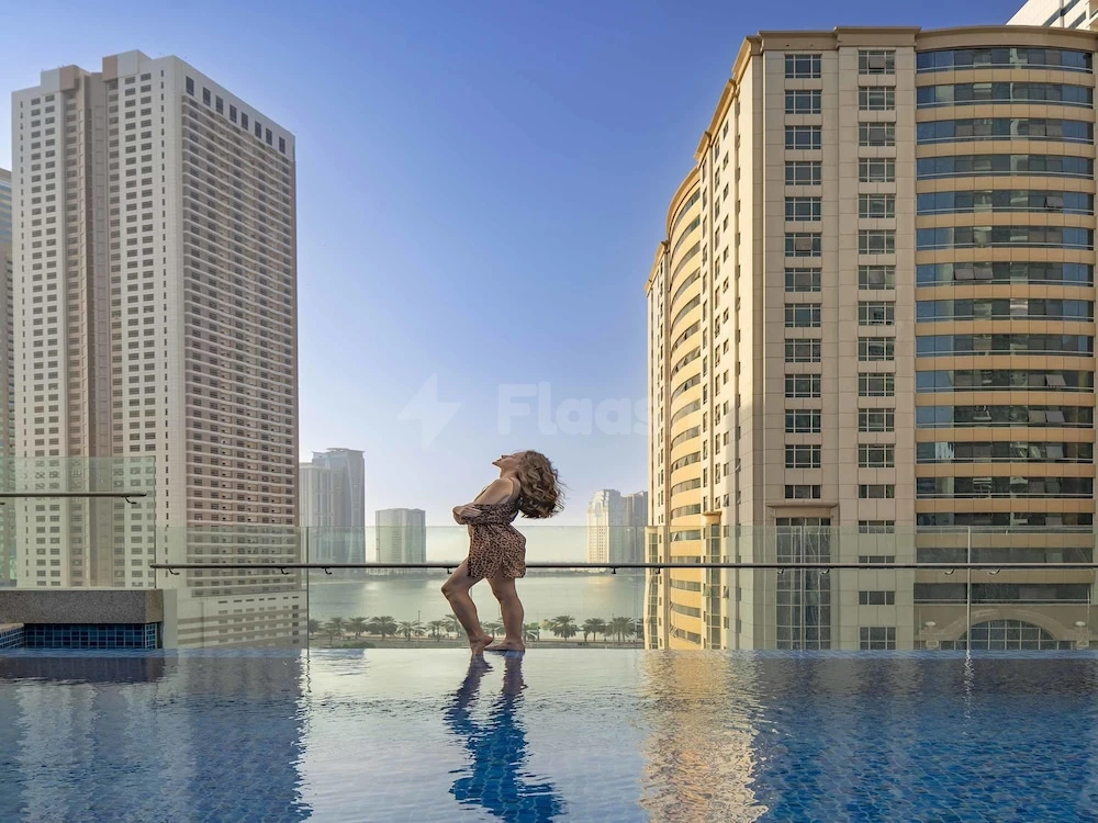 Infinity pool at Pullman Hotel Sharjah, Sharjah, reflecting city skyline and clear blue sky