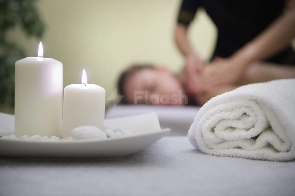 Spa treatment room at Pullman Hotel Sharjah, with lit candles on pebbles and a rolled white towel nearby