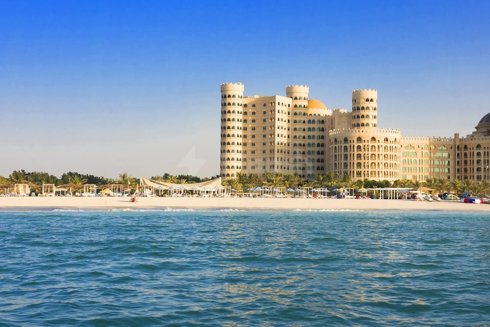 Beachfront view at Al Hamra Village Hotel, Ras Al Khaimah, featuring golden domes and palm-fringed shoreline