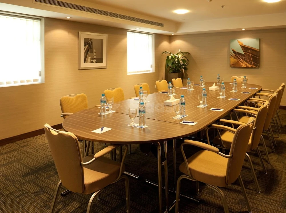 Conference room at Citymax Hotel Sharjah, with wooden table set for meeting and framed artwork on beige walls