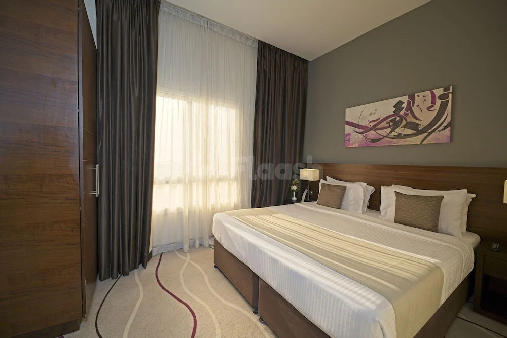 Guest room at Action Hotel Ras Al Khaimah, Ras Al Khaimah, featuring wooden headboard and abstract wall art