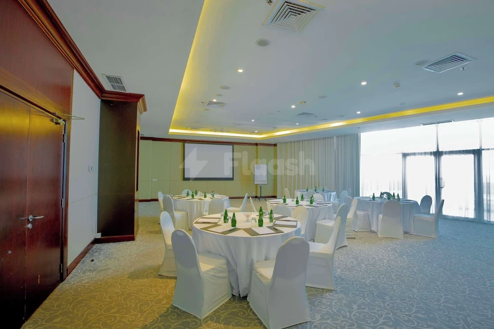 Banquet hall at Radisson Blu Resort Fujairah, Fujairah, with round tables and white chair covers under recessed lighting
