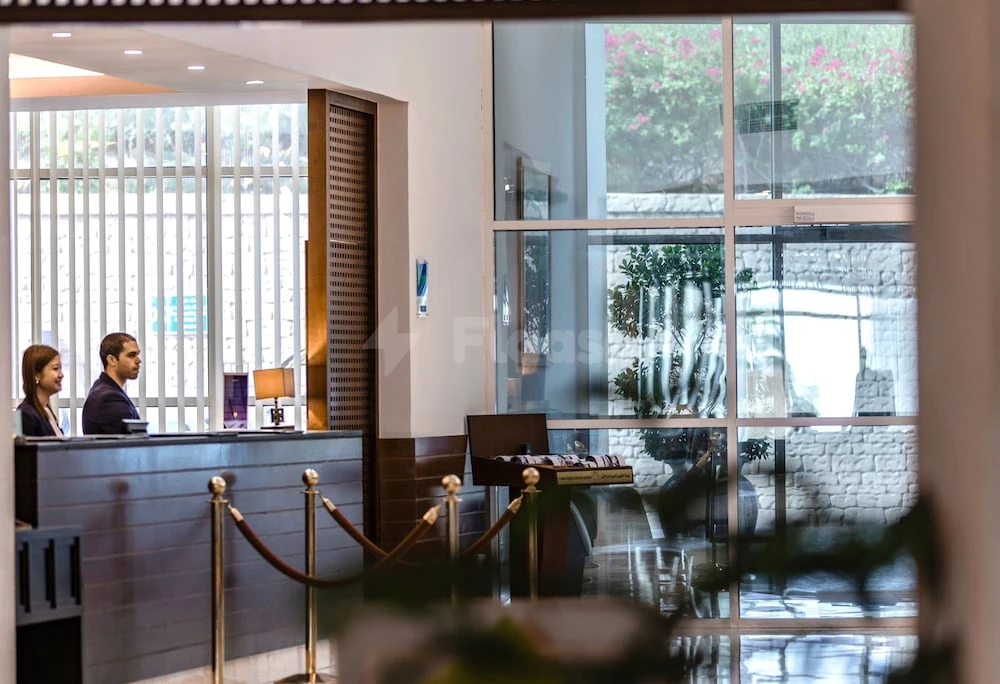 Lobby at Radisson Blu Resort Fujairah, Fujairah, with reception desk and large glass windows showing greenery outside