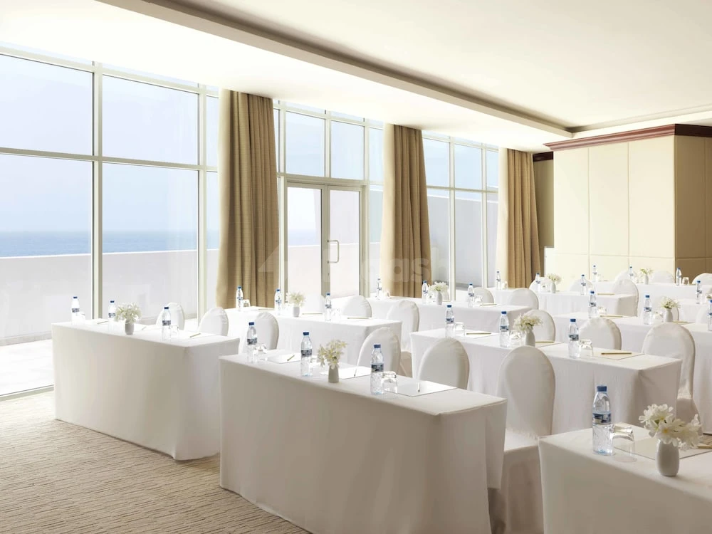 Meeting room at Radisson Blu Resort Fujairah, Fujairah, with sea view through glass walls and white linen tables