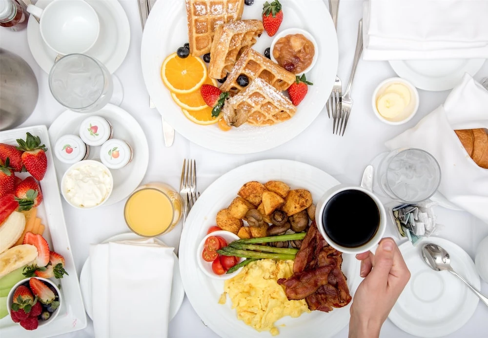 Breakfast spread at Golden Tulip Sharjah, Sharjah, with waffles and fresh fruit on white linens