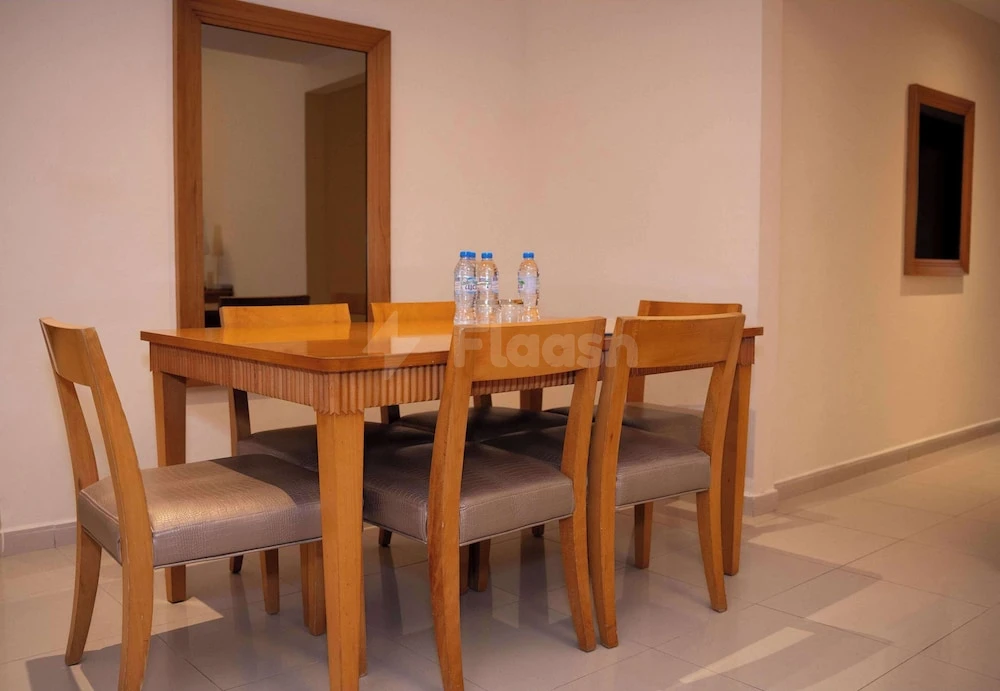 Dining area at Golden Tulip Sharjah, Sharjah, featuring wooden table with four chairs and water bottles on surface