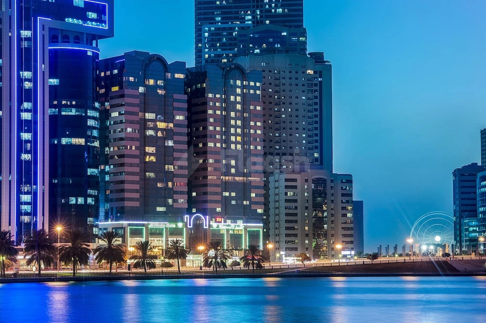 Lobby at Golden Tulip Sharjah, Sharjah, illuminated facade with palm trees along waterfront edge