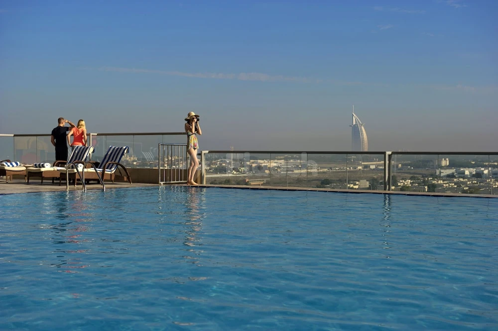 Infinity pool at Two Seasons Hotel & Apartments Dubai, Dubai, overlooking Burj Al Arab with glass railing and sun