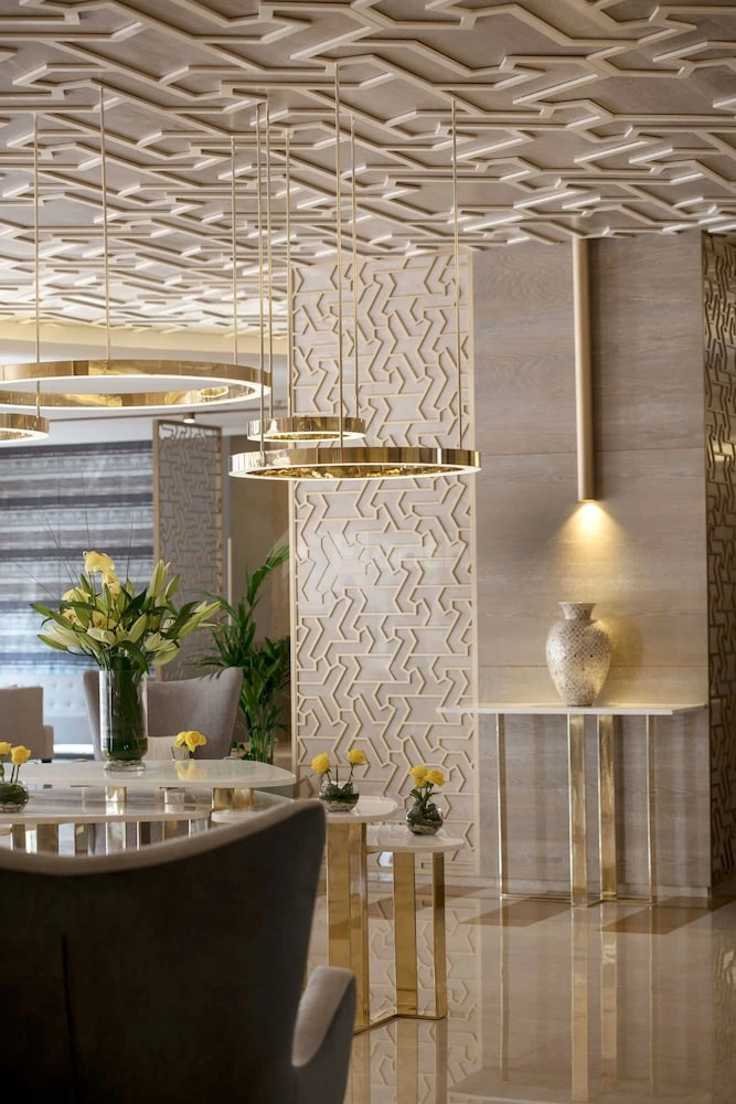 Lobby at Two Seasons Hotel & Apartments Dubai, featuring geometric ceiling panels and gold-accented pendant lights