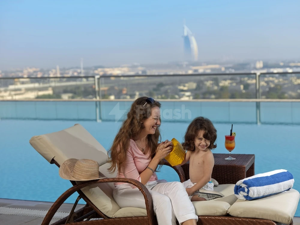 Rooftop infinity pool at Two Seasons Hotel & Apartments Dubai, with Burj Al Arab visible beyond glass railing