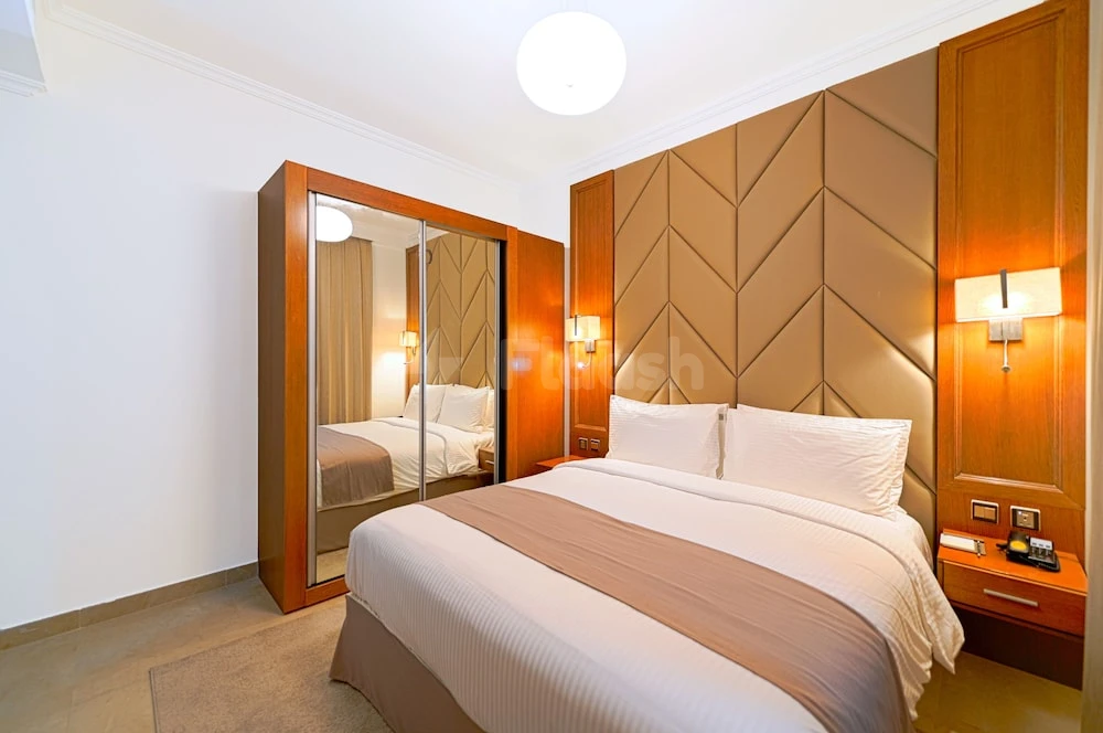 Bedroom suite at TIME Moonstone Hotel Apartments, Fujairah, featuring wooden paneling and mirrored wardrobe doors