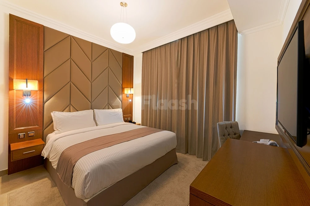 Guest room at TIME Moonstone Hotel Apartments, Fujairah, featuring geometric headboard and wall-mounted lamps