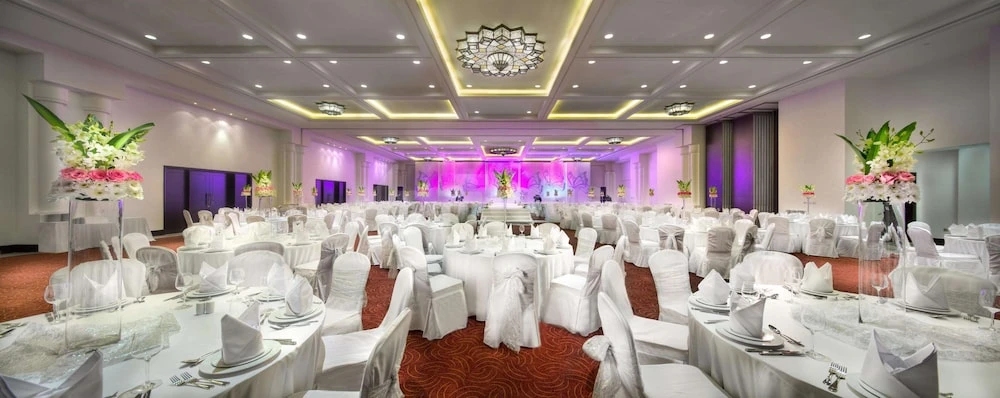 Banquet hall at Bahi Ajman Palace Hotel, Ajman, with white draped tables and ornate ceiling lights