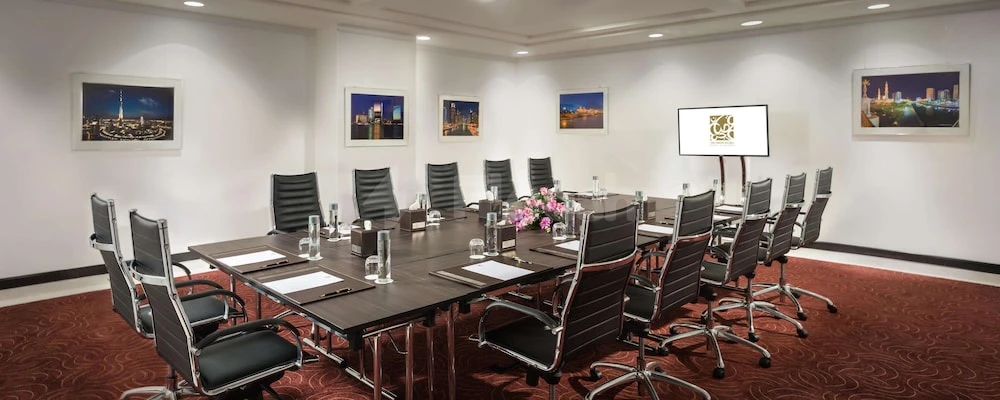 Boardroom at Bahi Ajman Palace Hotel, Ajman, with dark wood table and cityscape artwork on walls